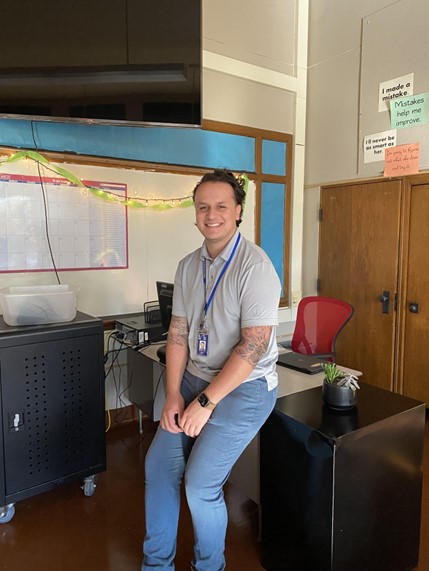 Alumnus Alex Bogart, pictured seated in his classroom.