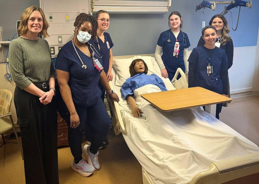 Group photo of physician assistant studies students standing next to a high-fidelity medical simulation mannequin which Canisius donated to Catholic Health. xt to