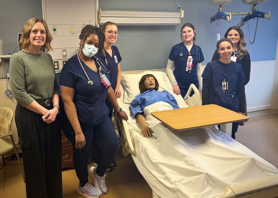 Group photo of physician assistant studies students standing next to a high-fidelity medical simulation mannequin which Canisius donated to Catholic Health. xt to