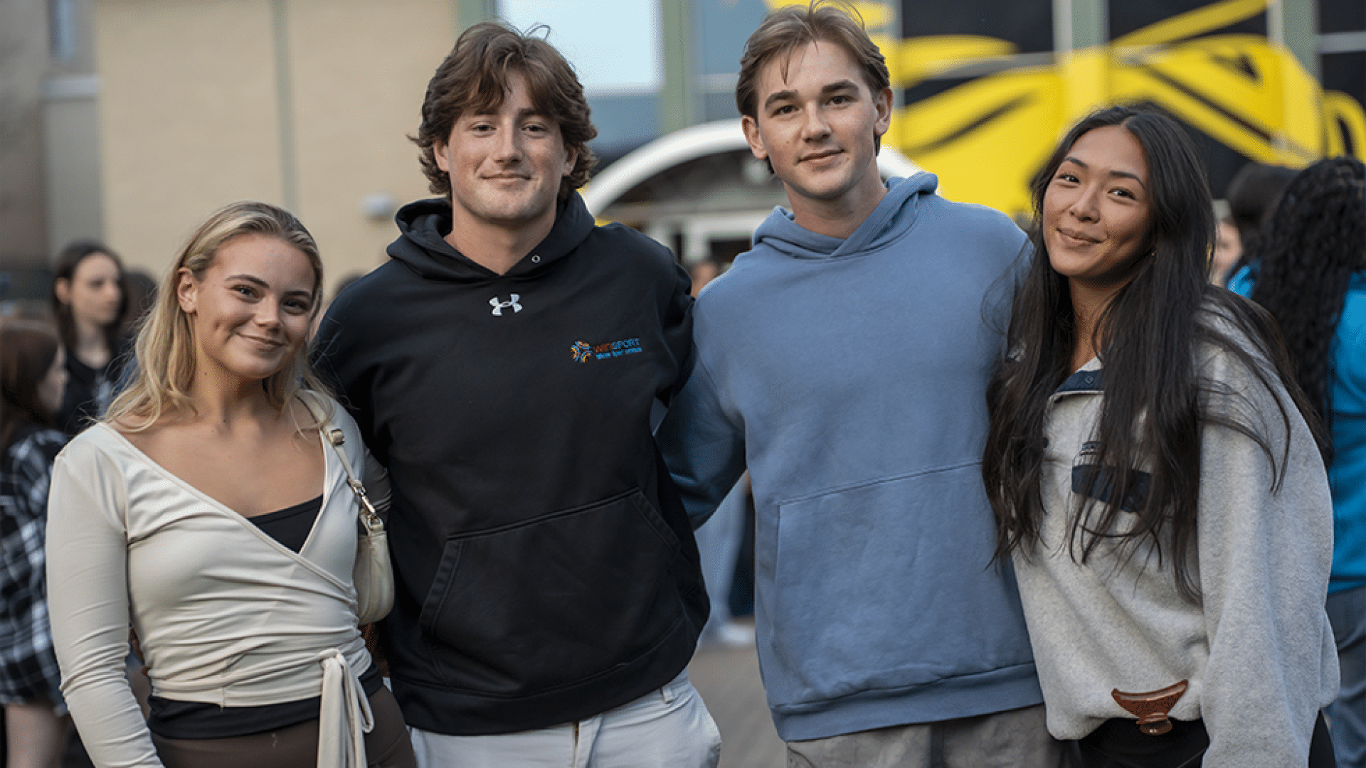 4 students on a college campus posing together