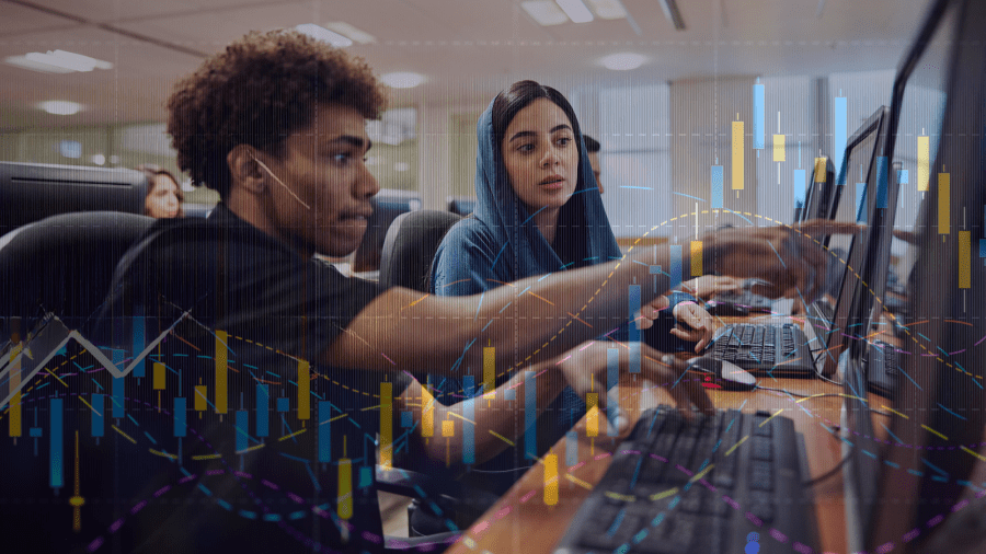 Two students work together at computers in a classroom, discussing data displayed on their screens. A transparent overlay of graphs and charts.