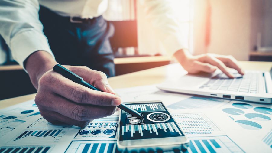 business man in an office looking at a chart on a phone with other data visualizations on the table