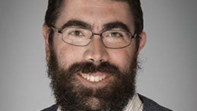 Photo of man with a beard wearing glasses. 