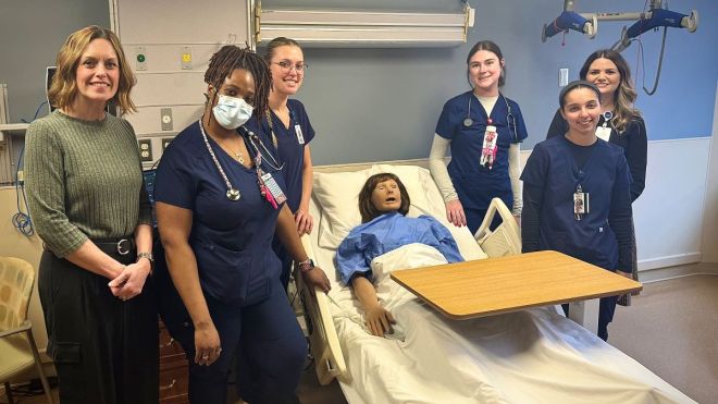 Group photo of physician assistant studies students standing next to a high-fidelity medical simulation mannequin which Canisius donated to Catholic Health. xt to