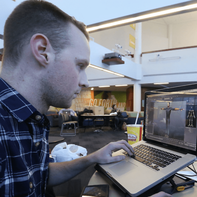 Student using a laptop in a college building commons area