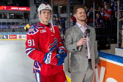 Griffin DellaPenna rinkside with a Rochester American's player