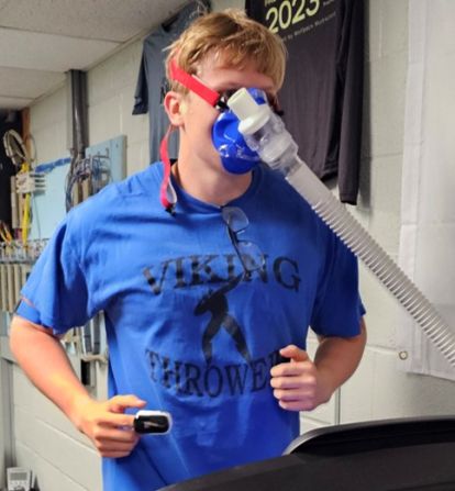 Man runs on treadmill wearing a mask.