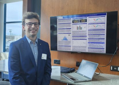 Student presenting at a college conference with data charts behind them on a screen
