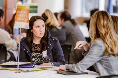 graduate student speaking to an admissions counselor at a college at a table with a flyer on it