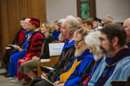 Canisius faculty wearing academic regalia listen from the pews of Christ the King Chapel during Mass of the Holy Spirit