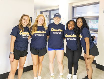 Students wearing matching shirts to celebrate college welcome week posing in a residence hall