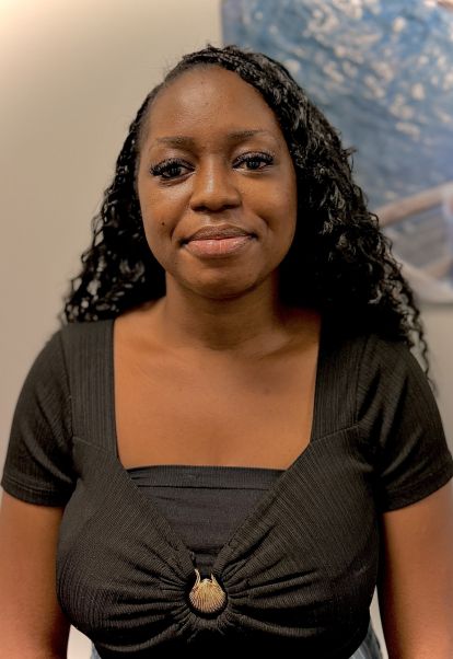 graduate student posing for professional headshot in front of a wall with a painting on it