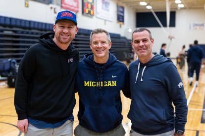 Three men with arms around the shoulders smiling.
